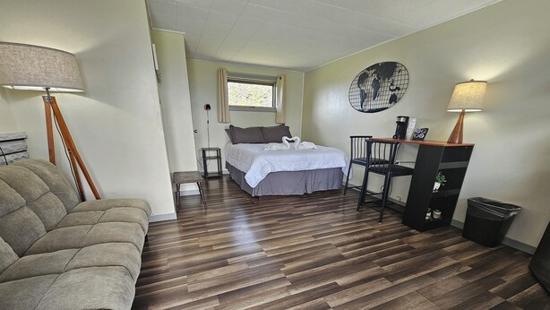 A bedroom with a bed, bedside table, lamp, and a desk with a chair. - The Last Resort (Hart)