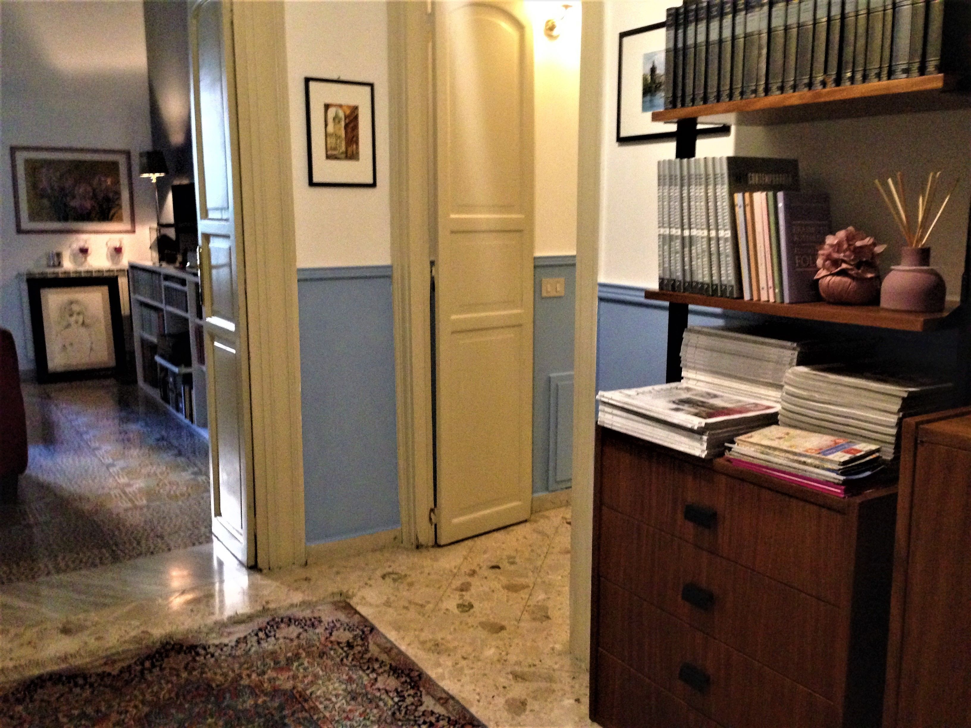A hallway with a wooden cabinet, a bookshelf, and a framed picture on the wall.