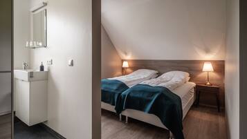 A bedroom with a bed, bedside lamps, a nightstand, and a wooden headboard.