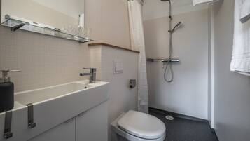 A modern bathroom with a glass shelf, white sink, and toilet.