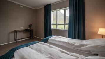 Un dormitorio con dos camas, un escritorio, una lámpara y una ventana con cortinas.