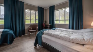 A hotel room with two beds, a desk, a chair, and large windows with curtains. - Holt Inn (Holt)