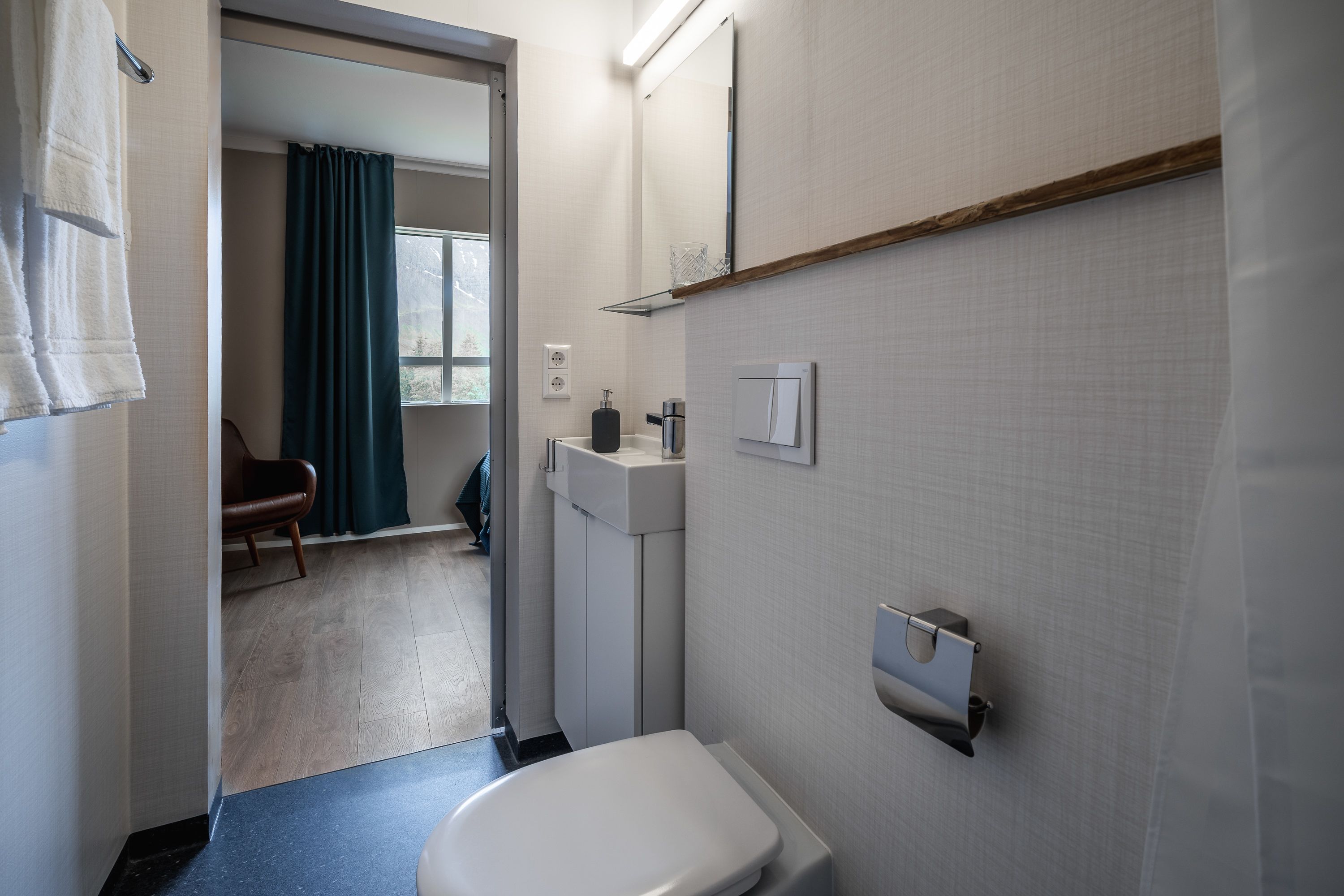 A modern bathroom with a toilet, sink, and mirror.