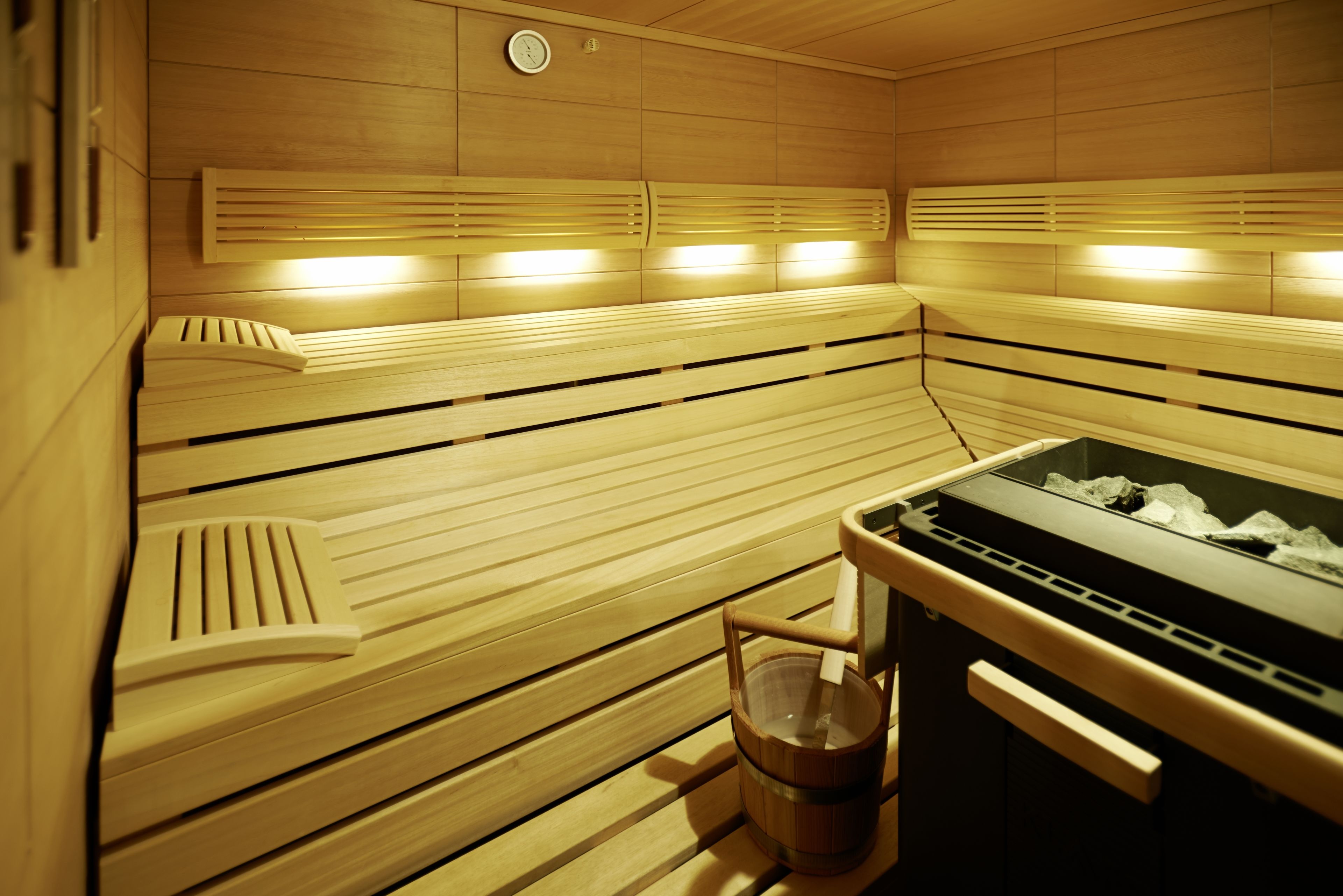 A sauna with wooden benches, a bench with a footrest, and a heater with ice.