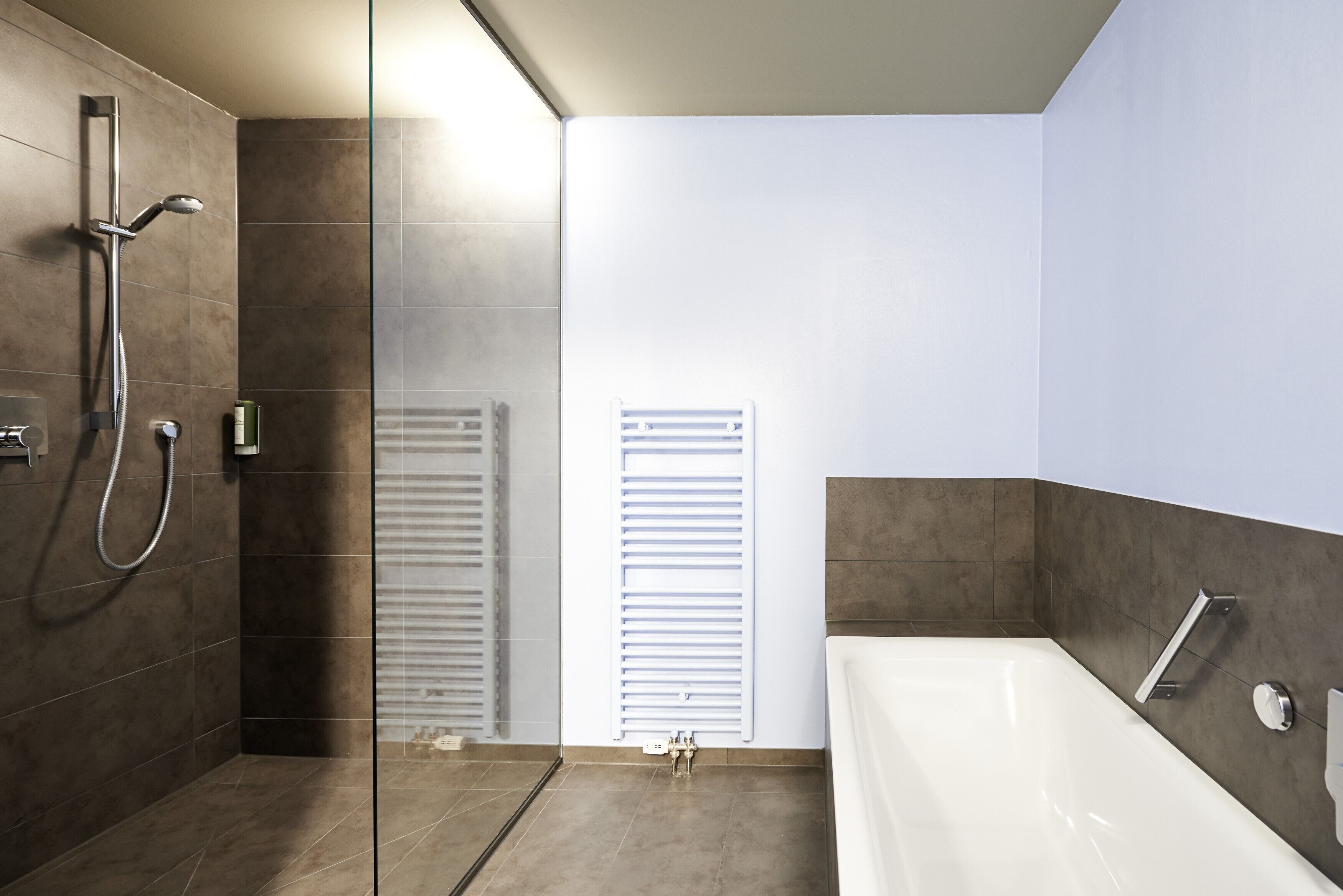 Un baño moderno con ducha a ras de suelo, bañera y mampara de vidrio.