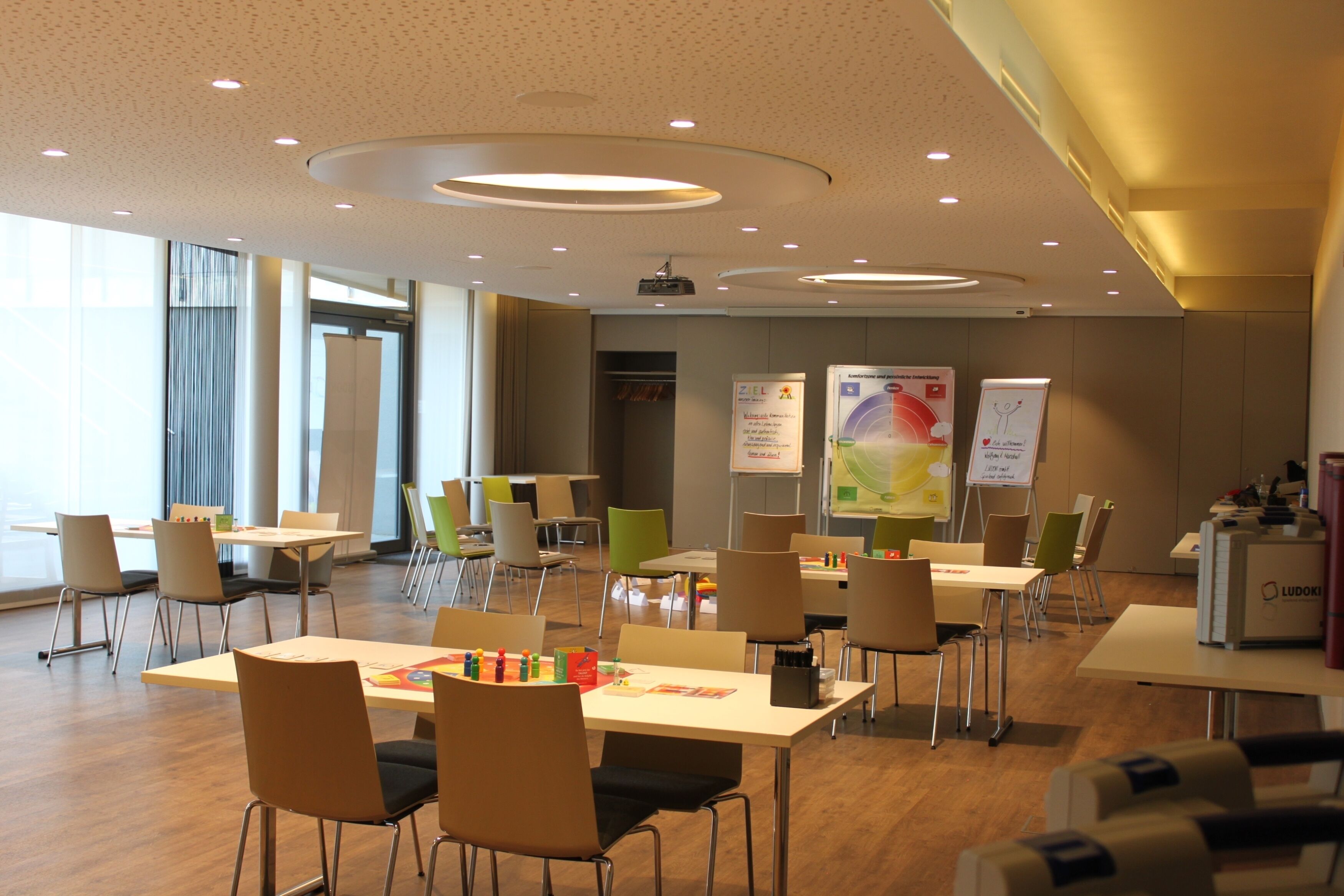 Ein Konferenzraum mit Tischen, Stühlen und einem Projektor.