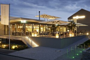 Un restaurante al aire libre con mesas y sombrillas, una escalera y un edificio con un letrero al fondo.