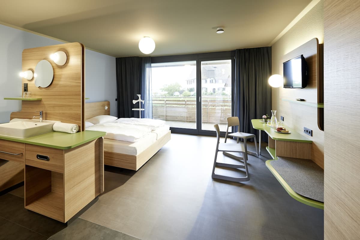 Una habitación de hotel moderna con tocador de madera, cama, escritorio y televisor.