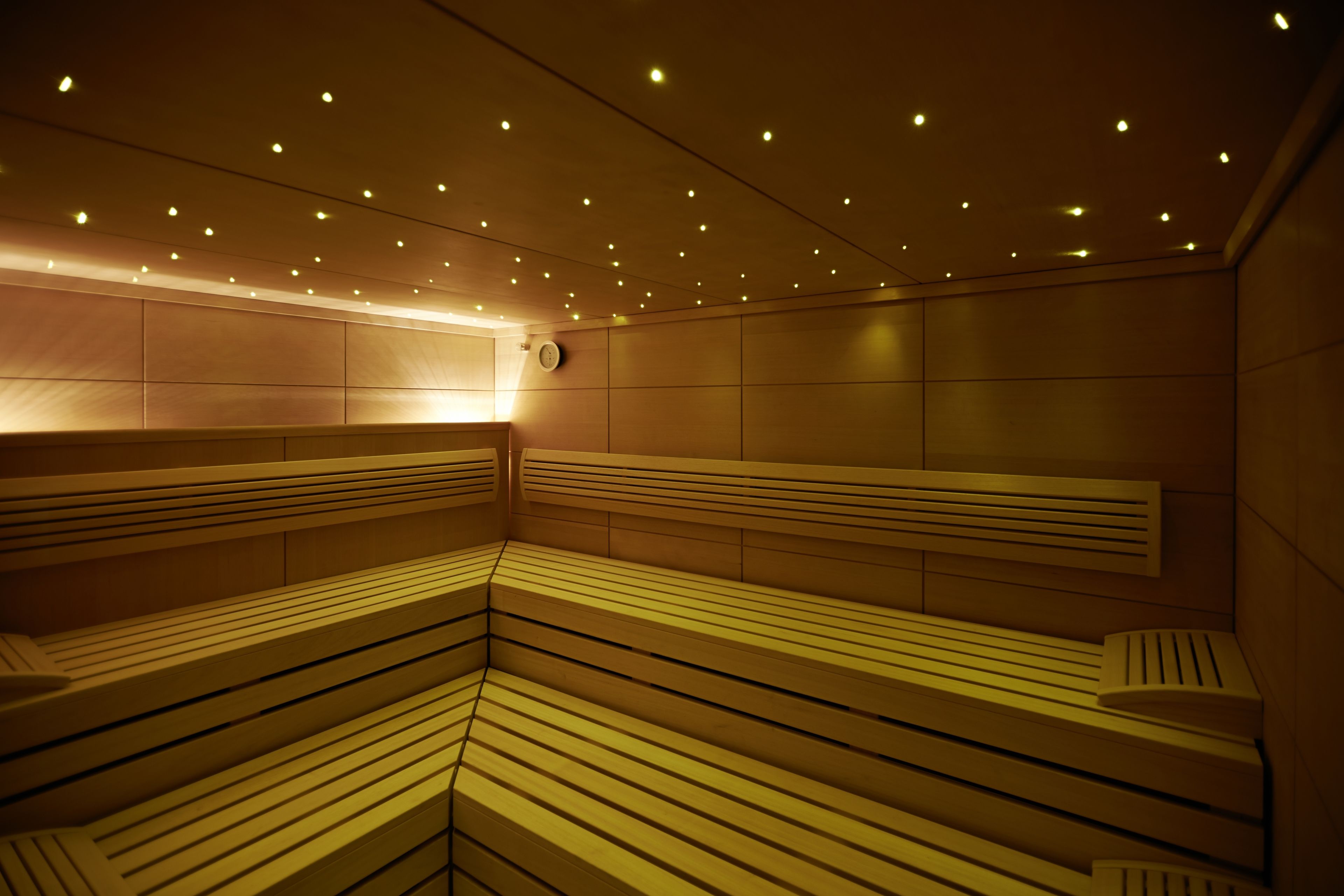 A sauna with multiple benches and a ceiling with evenly spaced lights.