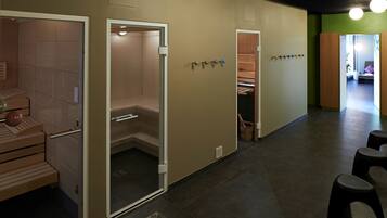 A sauna area with benches, a shower room, and a changing room with lockers.