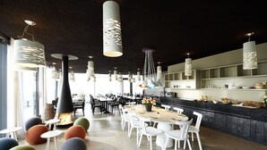 A modern dining area with round tables, white chairs, and unique hanging light fixtures.