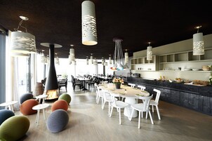Un comedor moderno con mesas redondas, sillas blancas y lámparas colgantes originales.