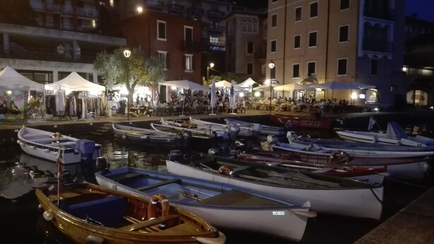 Un port de plaisance avec plusieurs bateaux amarrés, une foule de personnes et des bâtiments en arrière-plan.