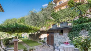 Une terrasse en pierre avec des sièges d’extérieur, un petit jardin et un mur en pierre doté d’une porte.