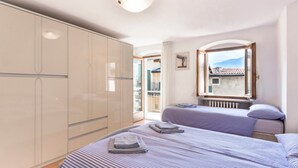 Une chambre avec deux lits, une grande armoire, une fenêtre donnant sur un beau paysage et un luminaire au plafond.