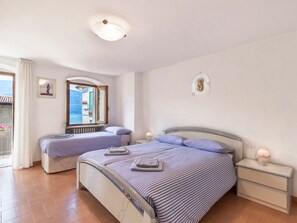 Hotellihuone, jossa on kaksi sänkyä, yöpöytä, ikkuna, josta on näkymä, ja kattovalaisin.