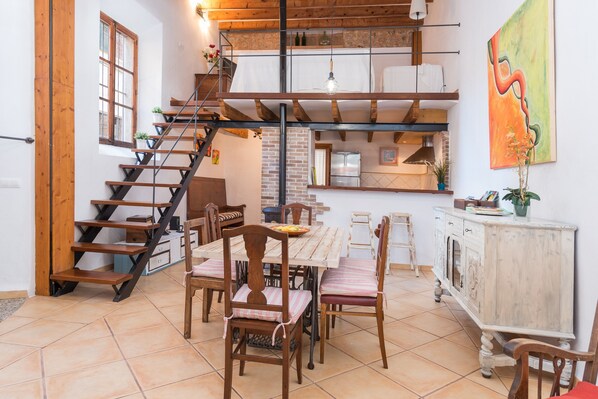 Un espace repas comprenant une table en bois, des chaises et un escalier menant à un niveau supérieur.