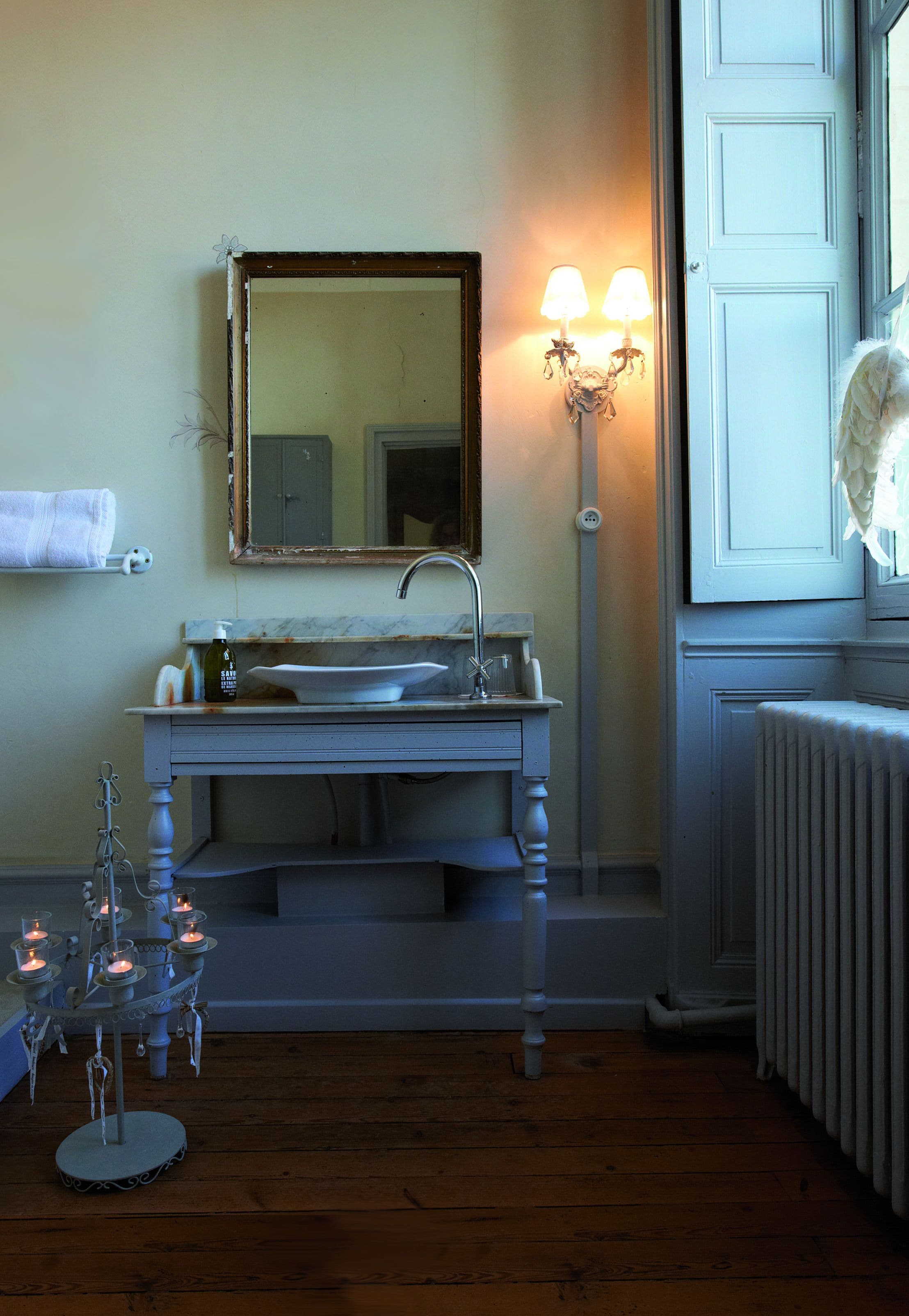 A bathroom with a sink, mirror, and wall-mounted light fixture.