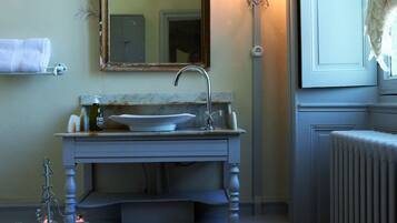 A bathroom with a sink, mirror, and wall-mounted light fixture.