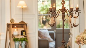 Una habitación acogedora con un candelabro, una escalera con plantas en macetas y una lámpara.