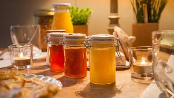 A breakfast table with jars of preserves, a candle, and a glass of orange juice.