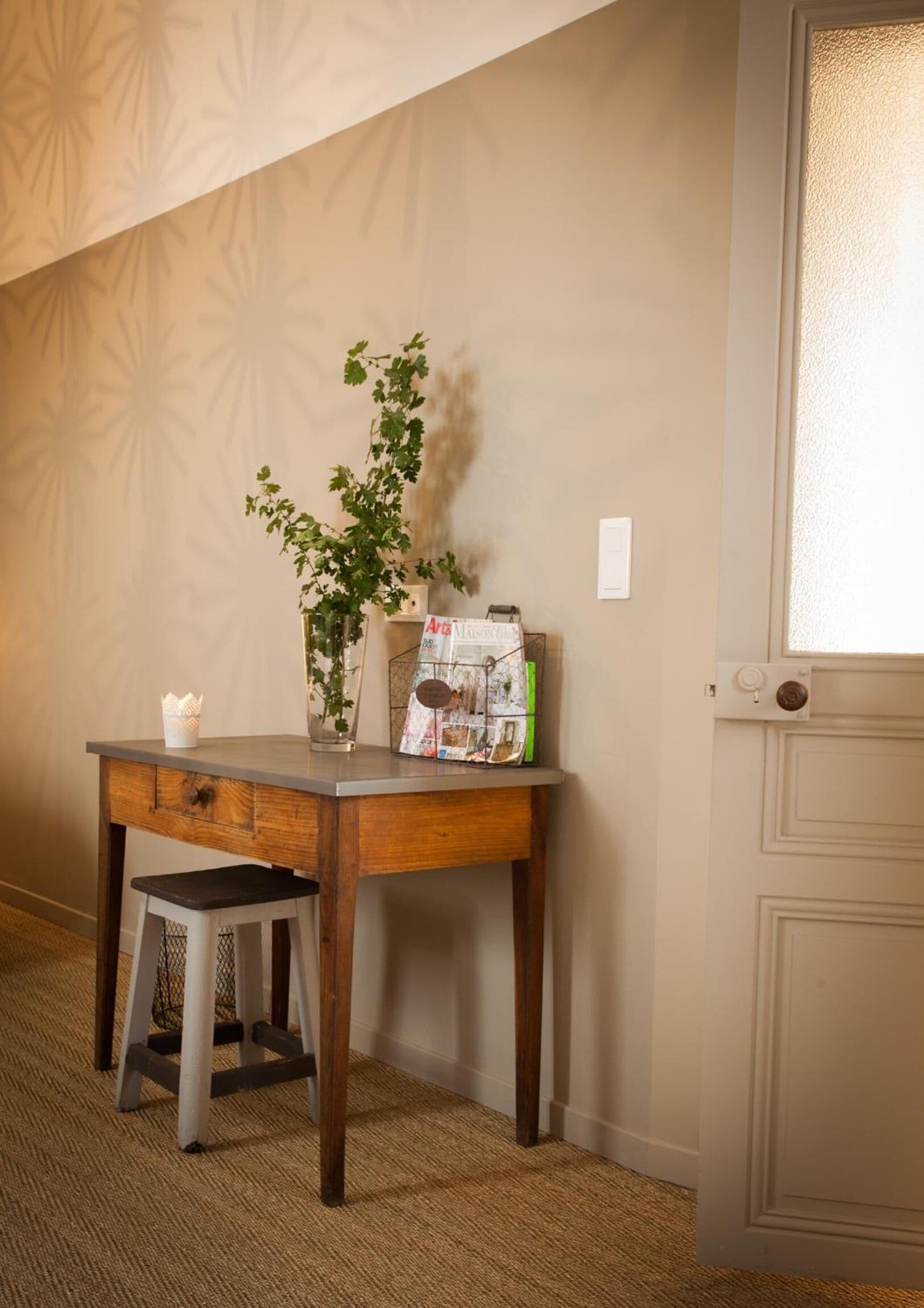 Un bureau d’angle agrémenté d’une plante, d’un porte-revues et d’un petit tabouret.
