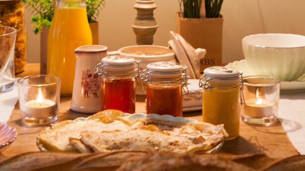 Una mesa de desayuno con diversos alimentos, una lámpara y velas.