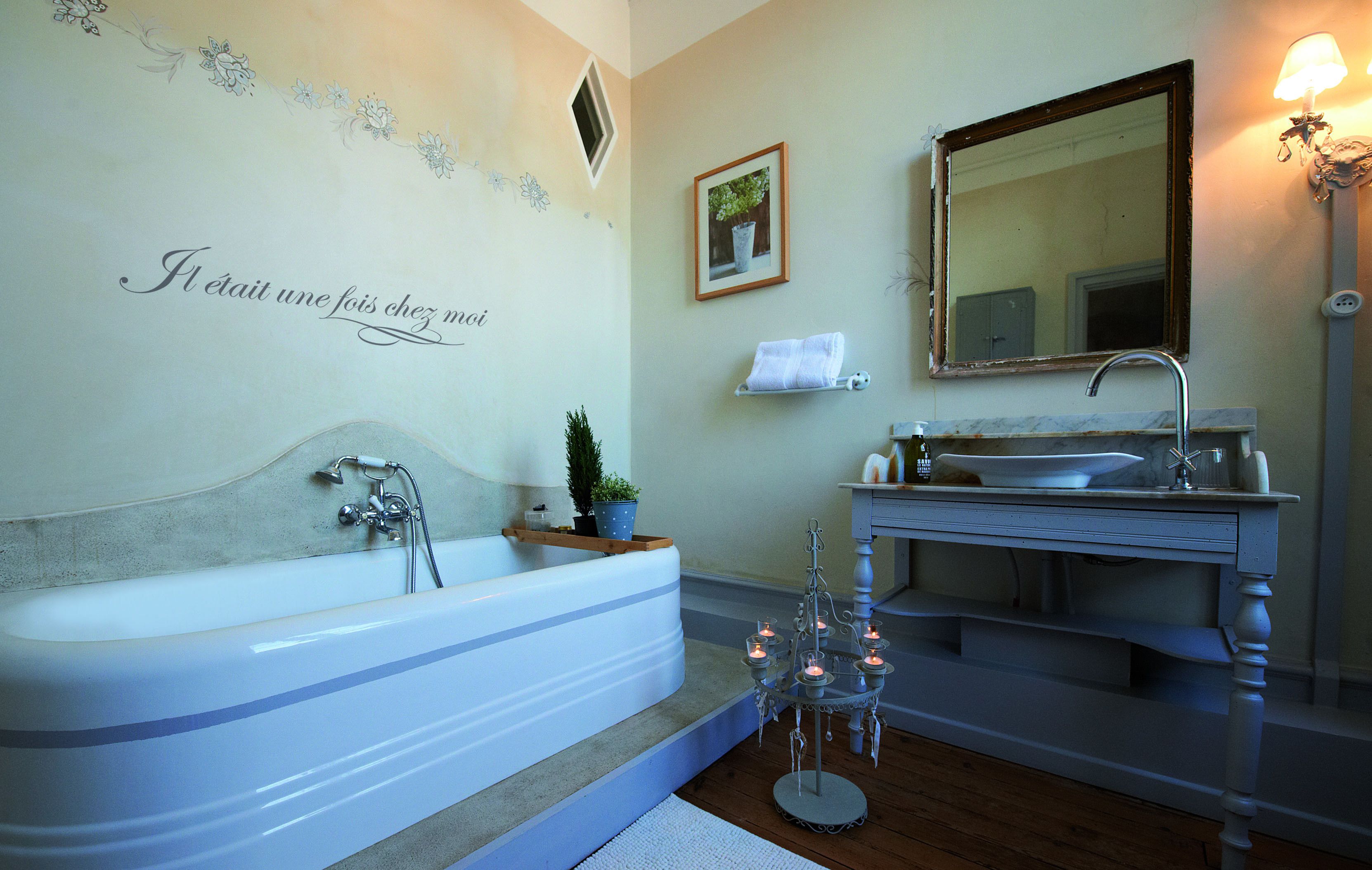 A bathroom with a freestanding bathtub, a sink, a mirror, and decorative candles.