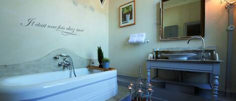 A bathroom with a freestanding bathtub, a sink, a mirror, and decorative candles.