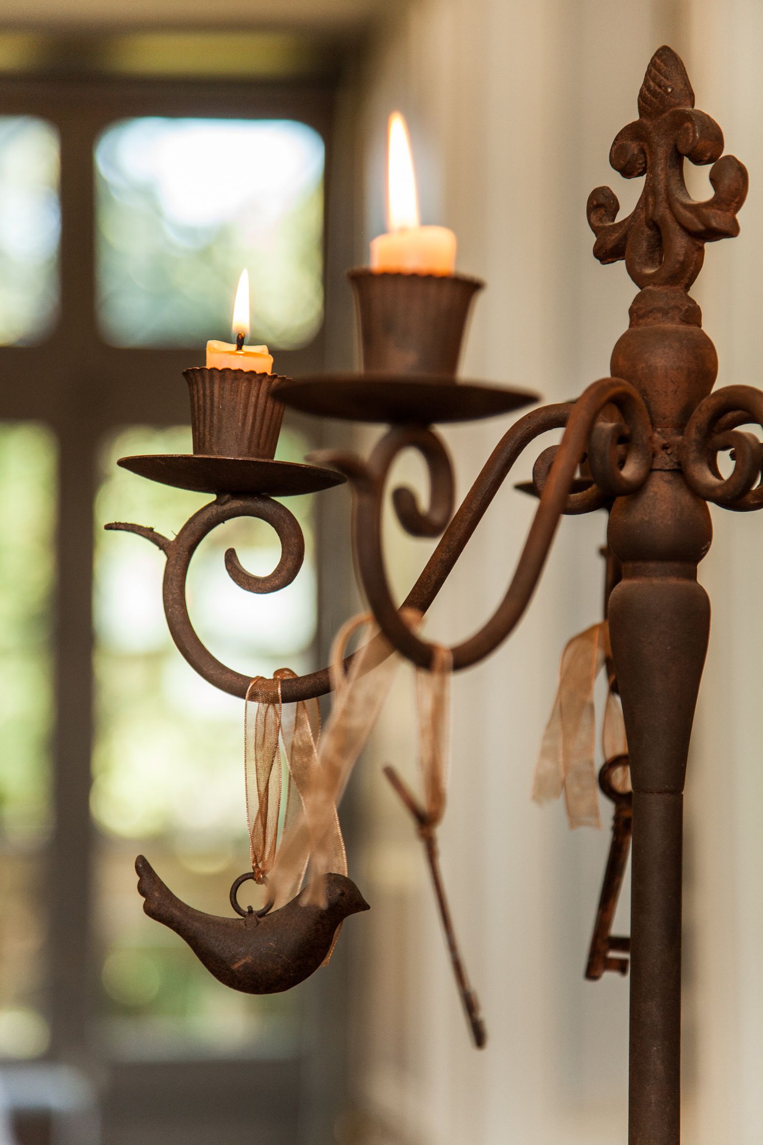 A candle holder with a bird-shaped candle holder and a lit candle.