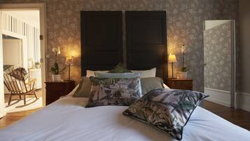 Una camera da letto con un letto grande, due comodini con lampade, una poltrona a dondolo e carta da parati floreale.