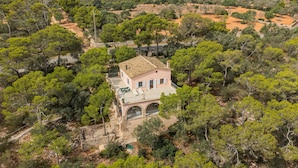 A single-story house with a tiled roof, surrounded by dense greenery and trees. - Villa Rosa – Cala Mondragó (Santanyí)