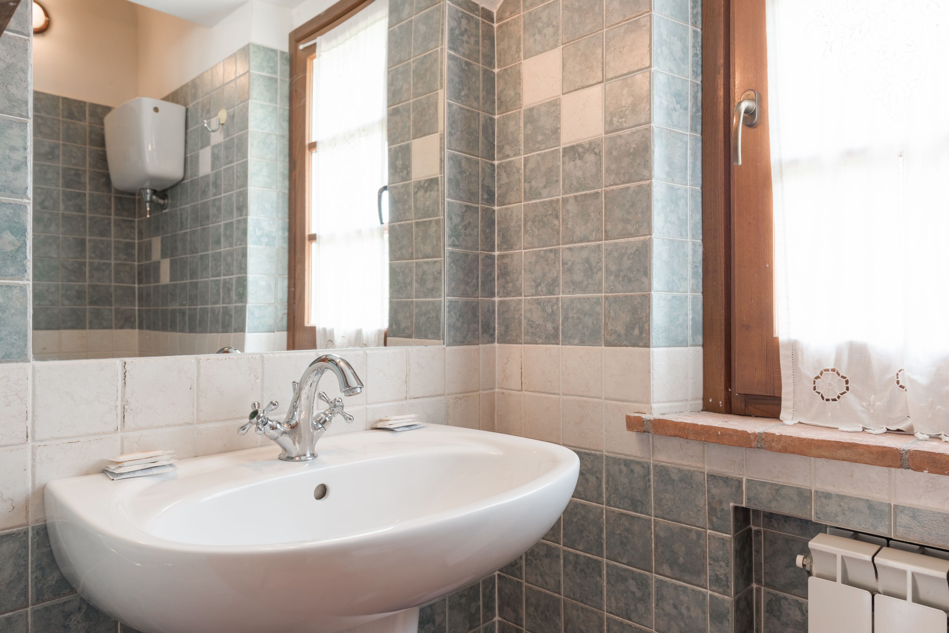 A bathroom with a white sink, a mirror, and tiled walls.