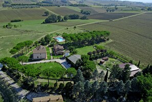 An aerial view of a rural property with multiple buildings, a swimming pool, and surrounding fields. - Poggio Verde (Castiglione del Lago)