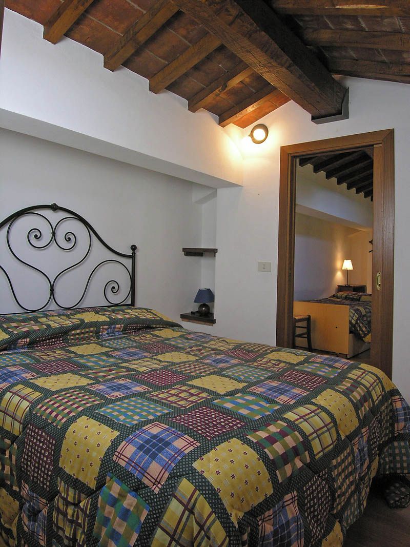 Un dormitorio con cama, mesita de noche, espejo y techo de madera.