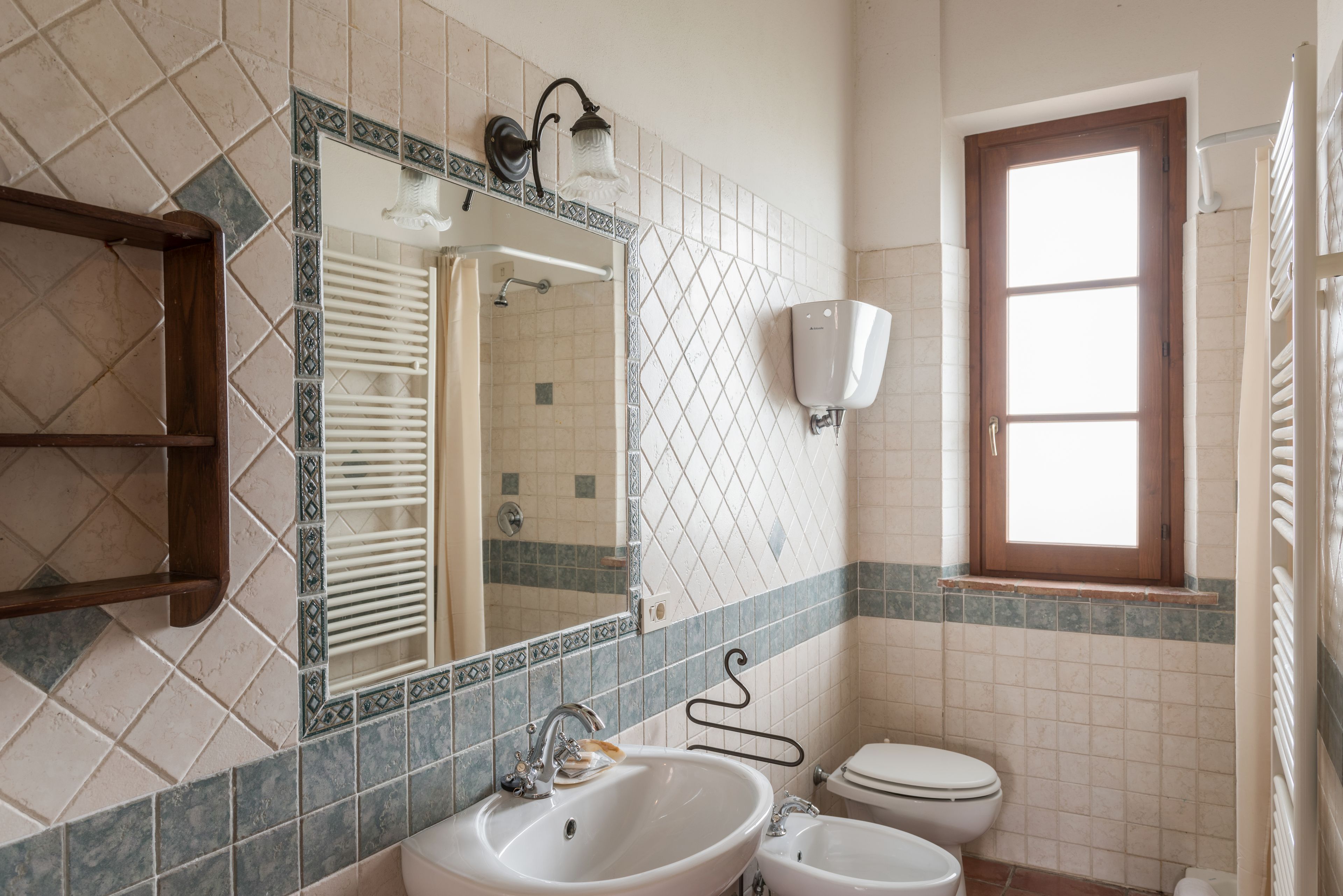 A bathroom with a large mirror, two sinks, a toilet, and a window.