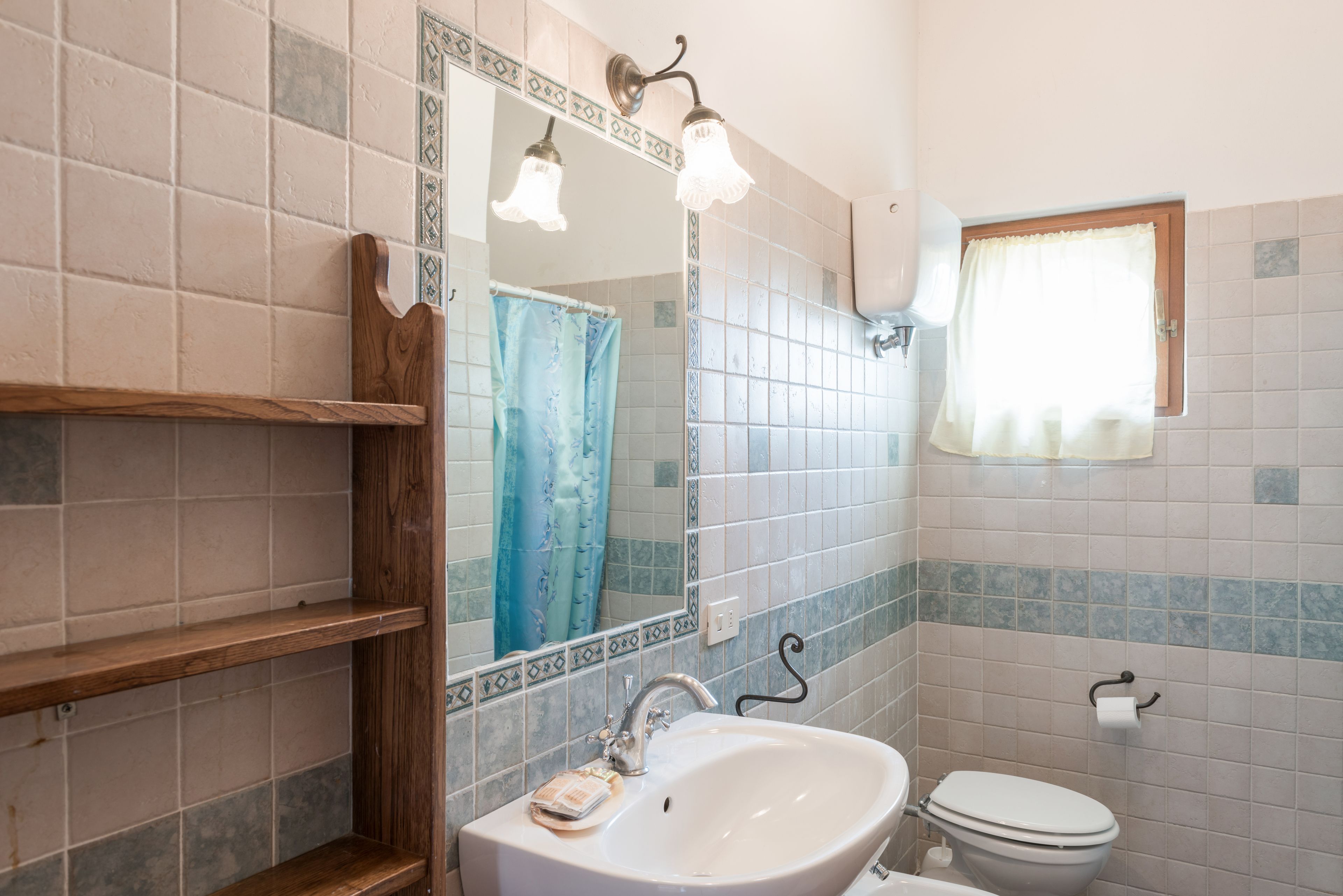 A bathroom with a white sink, a mirror, a shower curtain, and a toilet.