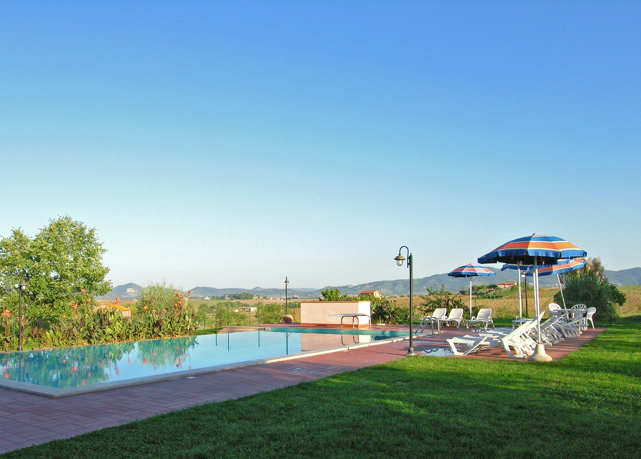 Een buitenzwembad, parasols bij het zwembad en ligstoelen