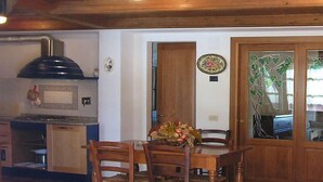 Ein Essbereich mit Holztisch und -stühlen, eine Küche mit Herd und Schränken sowie eine Treppe, die zu einer oberen Ebene führt.