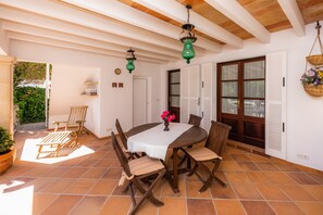Un patio con una mesa redonda, sillas y lámparas verdes colgantes.
