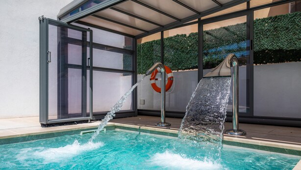 A swimming pool with water jets, a glass door, and a life buoy. - Central Holiday Home Near the Beach – Villa Amoros (Cala Ratjada)