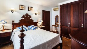 A bedroom with a wooden bed, two bedside tables, a nightstand, a wardrobe, and a door with a mirror. - Central Holiday Home Near the Beach – Villa Amoros (Cala Ratjada)