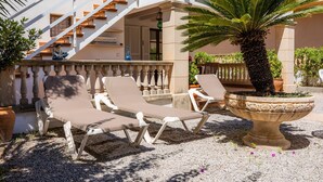 A terrace with lounge chairs, a palm tree, and a staircase. - Central Holiday Home Near the Beach – Villa Amoros (Cala Ratjada)