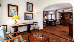 A living room with a sofa, armchair, coffee table, and a dining area with a table and chairs. - Central Holiday Home Near the Beach – Villa Amoros (Cala Ratjada)