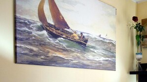 Un dipinto raffigura una barca a vela su mari agitati.