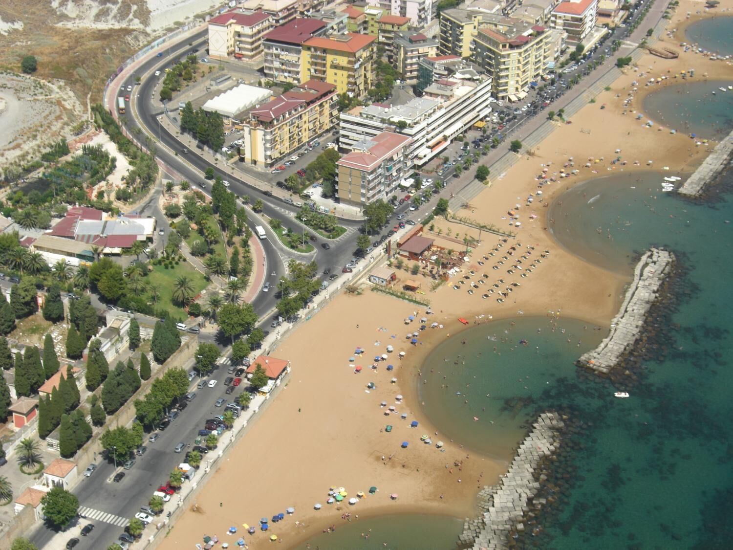 Vista aérea de una zona costera con playa, carretera y edificios.