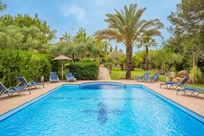 Una piscina con lettini e palme.