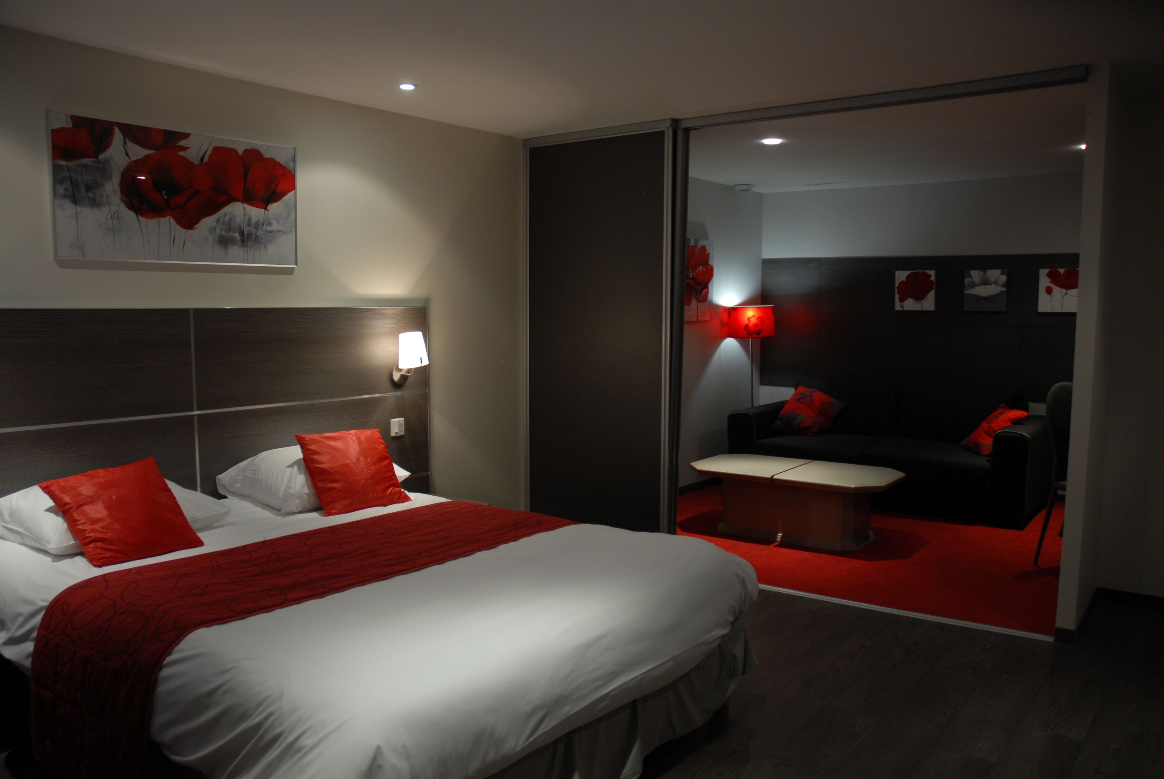 A modern hotel room with a large bed, a desk, and a sofa.