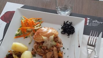 A dining table with a plate of food, cutlery, and glasses.