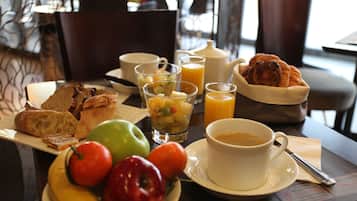 A breakfast setting with bread, fruits, juice, and coffee on a table.